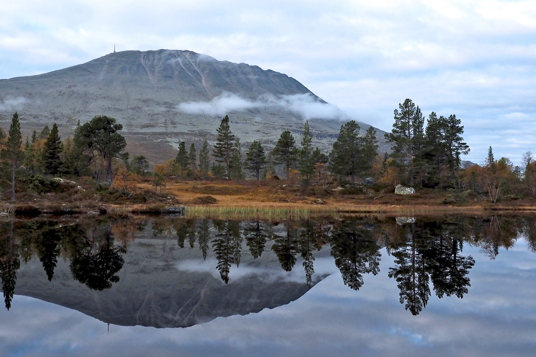 Gaustatoppen speglar sig i en stilla fjällsjö. Foto: Thomas Reinhardt.
