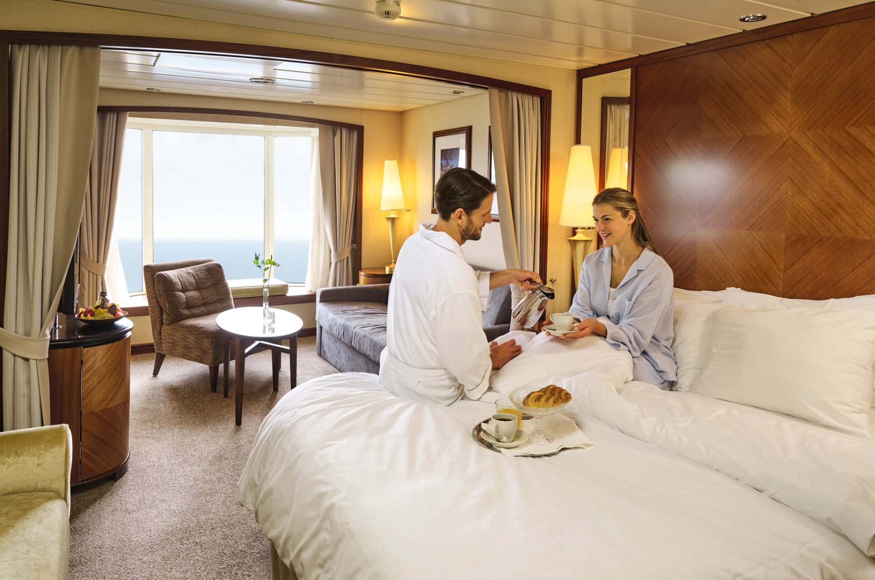 Paar trinkt Kaffee auf dem Bett in der Suite